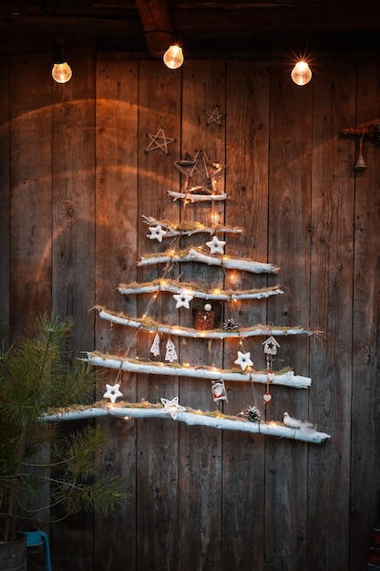 Árvore de natal na moda moderna minimalista em um fundo de madeira rústico. decorações de natal com suas próprias mãos em estilo rústico escandinavo.