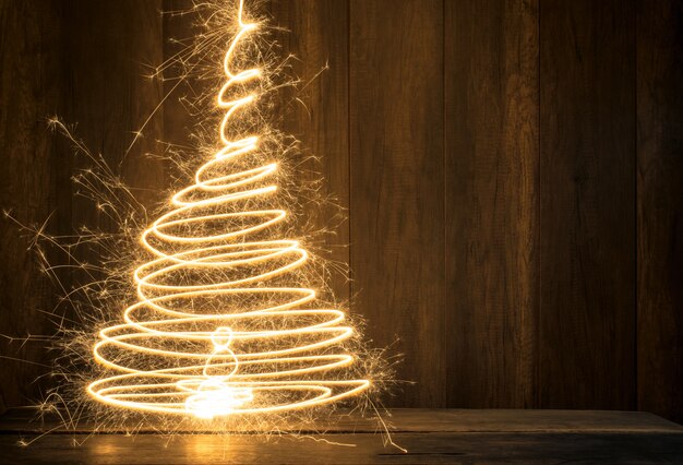 Árvore de natal simbólica abstrata criada usando sparklers com mesa de madeira e fundo da parede de madeira