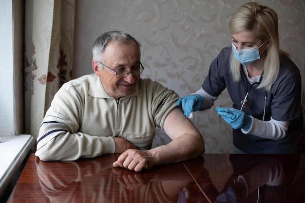 Arzt bereitet Impfschuss für ältere Patienten vor, indem er die Spritze zu Hause hält - Konzept der häuslichen Gesundheitskontrolle für Senioren während der Coronavirus-Covid-19-Pandemie.