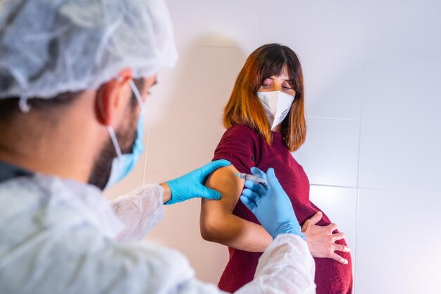 Arzt, der den neuen Impfstoff gibt, der für schwangere Frauen gegen Coronavirus-Antikörper zugelassen ist. Sie immunisieren die Bevölkerung. Nebenwirkungen riskieren Menschen, Antikörper covid19