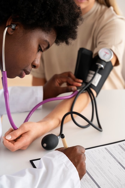 Foto arzt, der die blutdruckseitenansicht des patienten überprüft