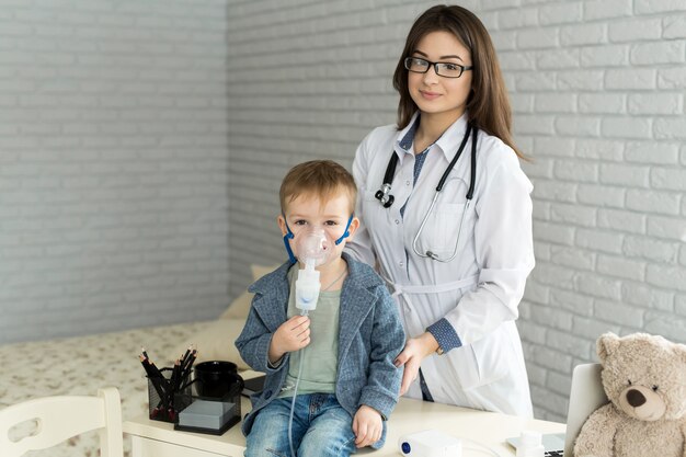 Arzt, der Medizininhalationsbehandlung auf einen kleinen Jungen mit Asthma anwendet