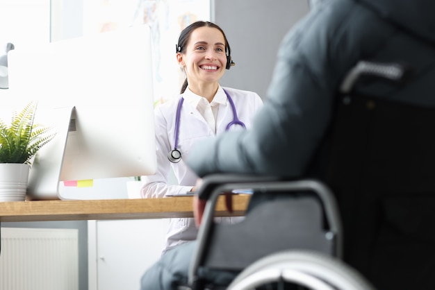 Arzt, der mit dem behinderten Patienten im Rollstuhl im Büro kommuniziert. Rehabilitation des Behindertenkonzepts