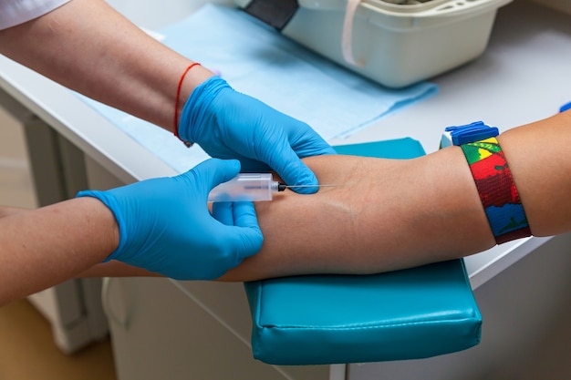 Arzt durchsticht eine Vene mit einer Nadel, Krankenschwester nimmt Blut aus den Venen am Arm