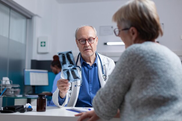 Arzt erklärt dem alten Patienten bei der Konsultation Röntgenergebnisse und Diagnose