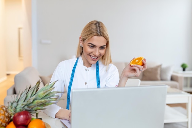 Arzt Ernährungsberater Anamnese schreiben im Büro Junge Frau Ernährungsberater verschreiben Rezept Weibliche Ernährungsberaterin sitzt am Tisch mit Laptop