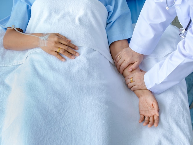 Arzt hält die Hand des Patienten auf dem Bett im Krankenhaus und überprüft das Nervensystem zur Heilung und Behandlung. Konzept des Guillain-Barre-Syndroms und der tauben Handkrankheit oder der Impfstoffnebenwirkung.
