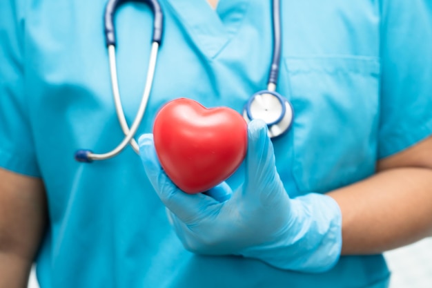 Arzt hält ein rotes Herz in der Krankenhausstation gesund starkes medizinisches Konzept