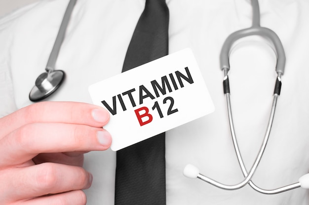 Arzt hält eine Karte mit dem Text VITAMIN B12