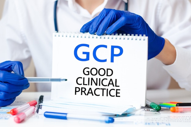 Arzt hält eine Karte mit Text GCP - Abkürzung für GOOD CLINICAL PRACTICE, medizinisches Konzept