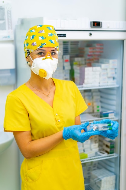 Arzt hält Medizinimpfstoff Anti-Virus-Gesundheitsbehandlung Medizinische Krankenschwester in Maske Apothekenlabor Forschungszentrum SicherheitsverfahrenRefrigirator mit medizinischem Hintergrund