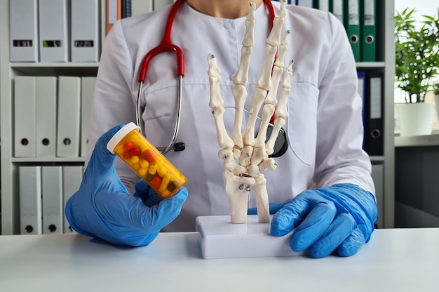 Arzt hält Pillen und Anatomie des Handskeletts