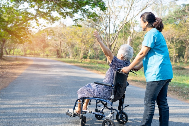 Arzt Hilfe und Pflege Asiatische Seniorin oder ältere alte Dame Patientin sitzt auf Rollstuhl im Park in Krankenstation, gesundes, starkes medizinisches Konzept.