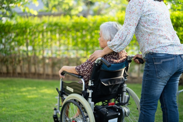 Arzt Hilfe und Pflege Asiatische Seniorin oder ältere alte Dame Patientin sitzt auf Rollstuhl im Park in Krankenstation, gesundes starkes medizinisches Konzept