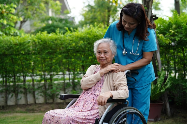 Foto arzt hilft behindertenpatientin einer asiatischen älteren frau, die im medizinischen konzept des parks im rollstuhl sitzt