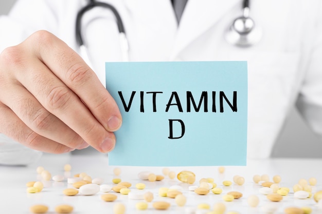 Arzt im Schlafrock hält einen Aufkleber mit Text Vitamin D.