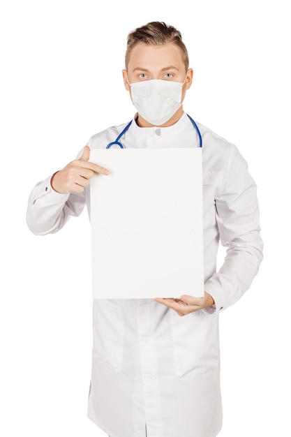 Arzt im weißen Kittel mit Stethoskop und Maske mit leerem Plakat, das Kopienraum für Produkt oder Text zeigt, isoliert auf weißem Studiohintergrund