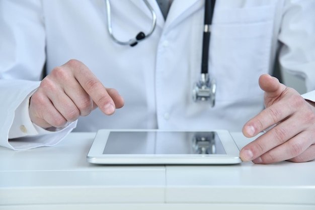 Arzt im weißen Kittel und Stethoskop mit digitalem Tablet