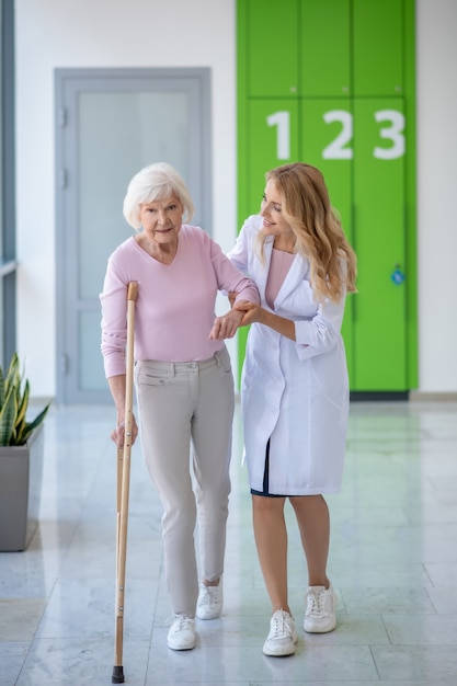 Arzt in einem Laborkittel und ein Patient, die zusammen in einem Korridor gehen