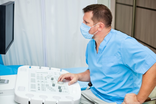 Arzt in Maske mit Ultraschallgerät
