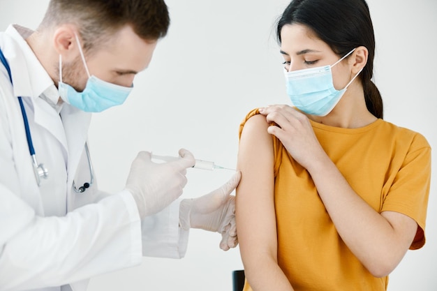 Arzt in medizinischer Maske injiziert einer Frau die Schulter Impfung Injektion Gesundheit Hochqualitätsfoto