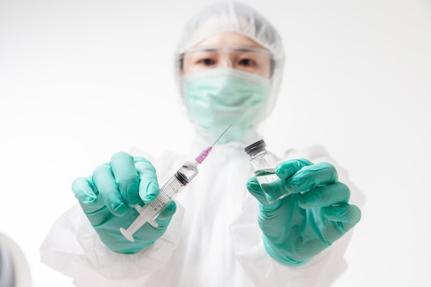 Arzt in Schutzanzug PSA mit Gesichtsmaske, die im Labor schützt, hält eine Flasche und eine Spritze für einen flüssigen Impfstoff für Medizin, medizinischer Arbeiter, der Covid-19-Impfstoff durchführt, Prävention Coronavirus-Strategie