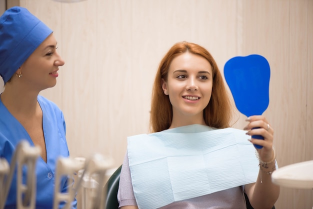 Arzt in Uniform, der die Zähne der Patientin in der Zahnklinik überprüft.