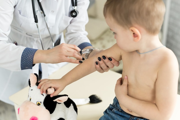 Arzt Kinderarzt, der dem Kind eine intramuskuläre Injektion in den Arm gibt