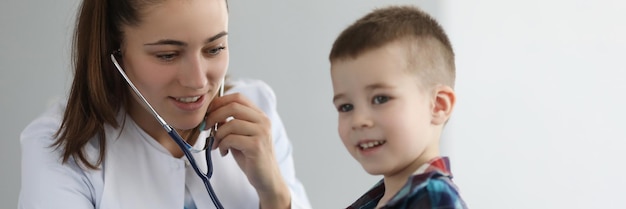 Arzt Kinderarzt hört auf Herz mit Stethoskop für kleinen Jungen in der Klinik