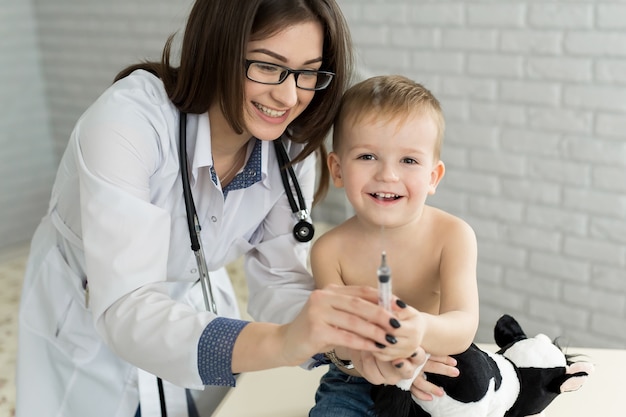 Arzt Kinderarzt spielt vor der Injektion mit dem Jungen.
