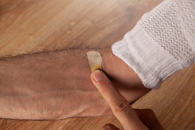 Arzt klebt Klebeband auf die Hand eines Mannes