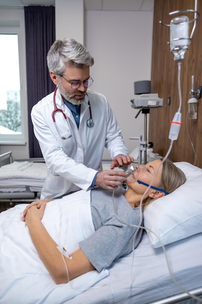 Arzt legt einer weiblichen Patientin eine Sauerstoffmaske auf