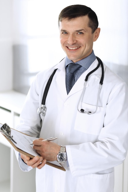 Arzt Mann mit Zwischenablage zum Auffüllen von Aufzeichnungen über die Medikamentenhistorie. Perfekter medizinischer Service in der Klinik. Arzt bei der Arbeit im Krankenhaus. Medizin- und Gesundheitskonzepte.