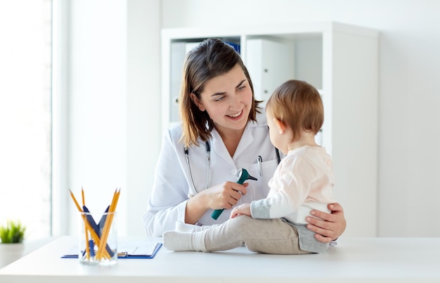 Arzt mit Baby und Otoskop in der Klinik