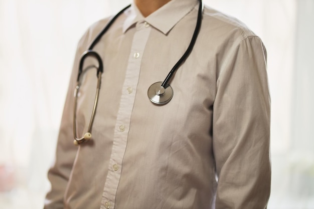 Arzt mit einem Stethoskop auf Krankenhaushintergrund Ein Arzt in einem weißen Kittel mit einem Stethoskop