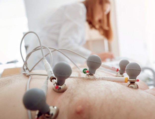 Foto arzt mit elektrokardiogramm-ausrüstung, der kardiogramm-test zum patienten in der klinik macht.