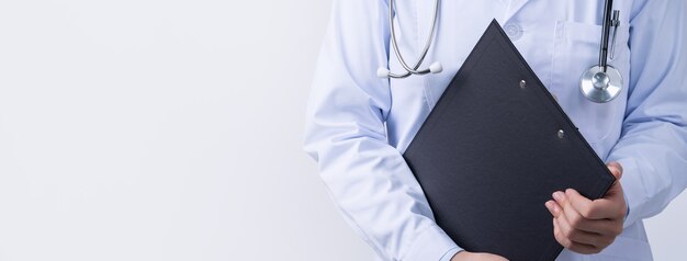 Arzt mit Stethoskop im weißen Kittel, der Zwischenablage hält, Krankenaktendiagnose schreibt, isoliert auf weißem Hintergrund, Nahaufnahme, beschnittene Ansicht.