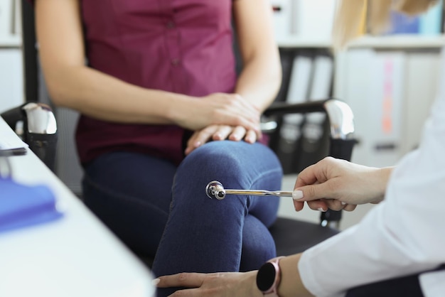 Arzt, Neurologe, der die Kniereflexe einer Patientin mit Schlaghammer in der Klinik überprüft