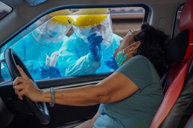 Foto arzt oder krankenschwester, die eine ppe-n95-maske, einen gesichtsschild und eine persönliche auto-straßenuntersuchung auf das covid-19-virus tragen