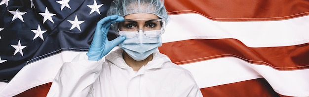 Arzt oder Krankenschwester mit medizinischer persönlicher Schutzausrüstung PSA gegen die Bannergröße der amerikanischen Flagge