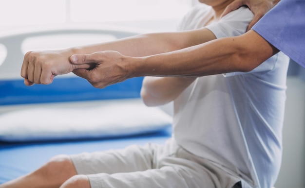 Foto arzt oder physiotherapeut, der die behandlung des verletzten arms eines athleten untersucht, männlicher patient, der sich ausdehnt und trainiert die rehabilitationstherapie schmerzen in der klinik durchführen