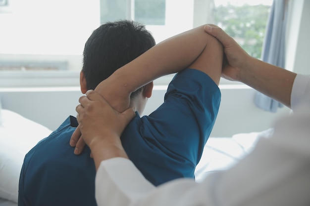 Arzt oder Physiotherapeut, der die Behandlung des verletzten Arms eines Athleten untersucht, männlicher Patient, der sich ausdehnt und trainiert Die Rehabilitationstherapie Schmerzen in der Klinik durchführen