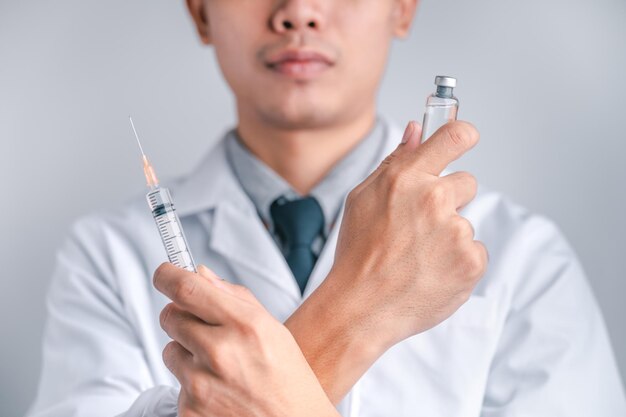 Arzt oder Wissenschaftler trägt eine Spritze und einen Impfstoff gegen COVID19-Impfung und Laborexperimente Konzept des Schutzes gegen das COVID19-Virus
