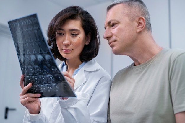 Foto arzt schaut mit patient über ct-scan