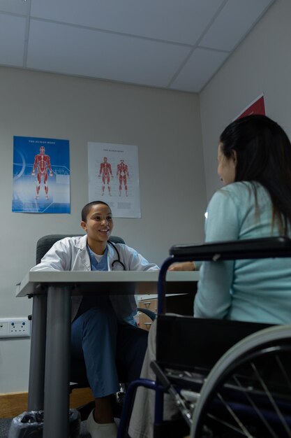 Foto arzt spricht mit einer behinderten patientin im untersuchungsraum