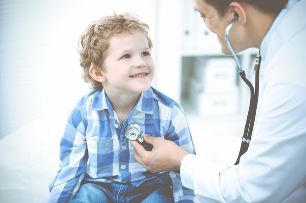 Arzt und geduldiges Kind. Arzt untersucht kleinen Jungen. Regelmäßiger Arztbesuch in der Klinik. Medizin- und Gesundheitskonzept.