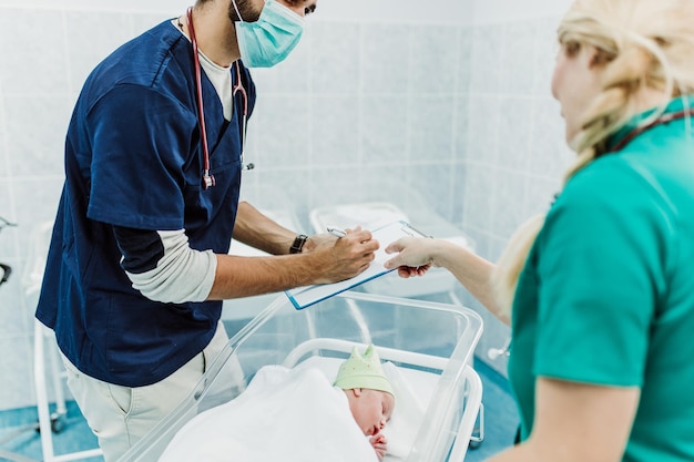 Arzt und Krankenschwester untersuchen Neugeborene im Krankenhaus.