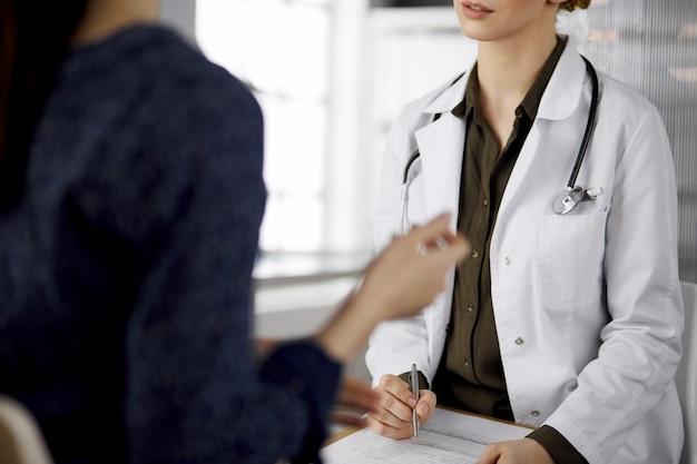 Arzt und Patient besprechen die aktuelle Gesundheitsuntersuchung, während sie in der Klinik sitzen. Perfekte medizinische Versorgung im Krankenhaus. Medizin-Konzept.