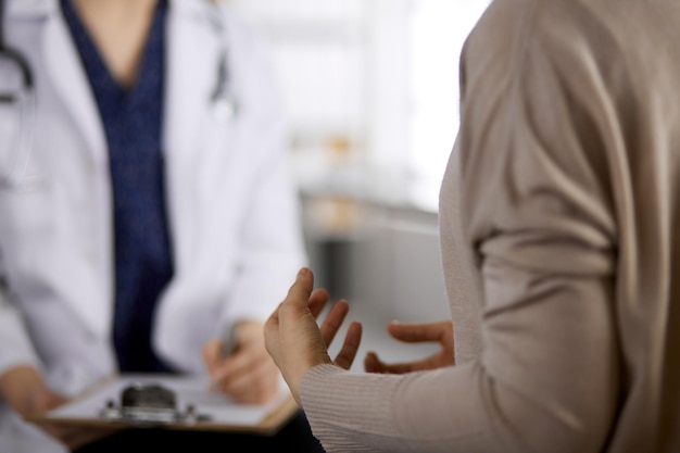 Arzt und Patient besprechen die aktuelle Gesundheitsuntersuchung, während sie in der Klinik sitzen. Perfekter medizinischer Service im Krankenhaus. Medizinkonzept.