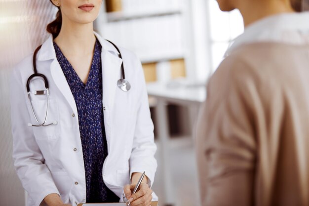 Arzt und Patient besprechen die aktuelle Gesundheitsuntersuchung, während sie in einer sonnigen Klinik sitzen. Perfekte medizinische Versorgung im Krankenhaus.